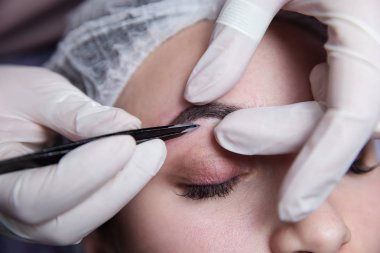 Kaş yapma süreci. Prosedürü kapalı gözleri ile güzel kadın.