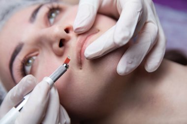 Dudaklar için kalıcı makyaj. Genç kadın bir güzellik stüdyosunda kalıcı oluyor.