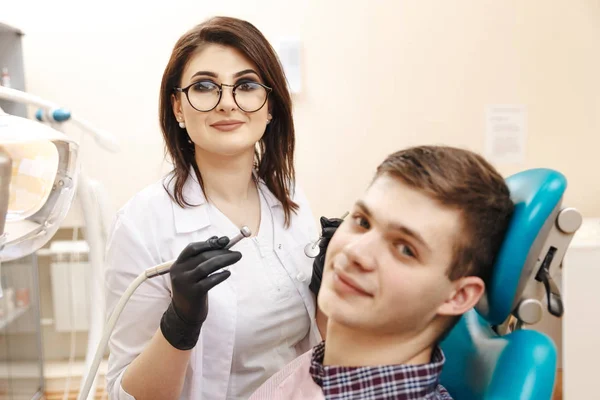 Foto de una joven dentista y un joven paciente masculino en la sala de dentistas . — Foto de Stock