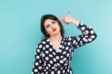 Mavi arka planda parmaklarıyla silah taklit kadın.