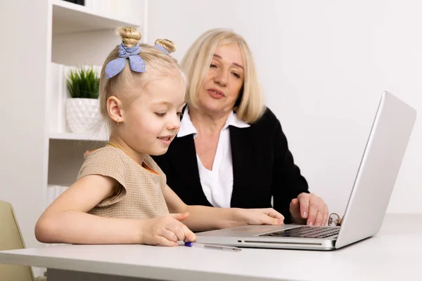 Leraar met klein meisje typen op de laptop in de klas. — Stockfoto