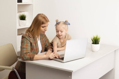 Anne ve kızı evde birlikte bilgisayar oynuyor.