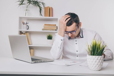 Ofis adam yorgun ve kötü hissediyorum. Sinirli adam bilgisayar önünde başını tutarak.