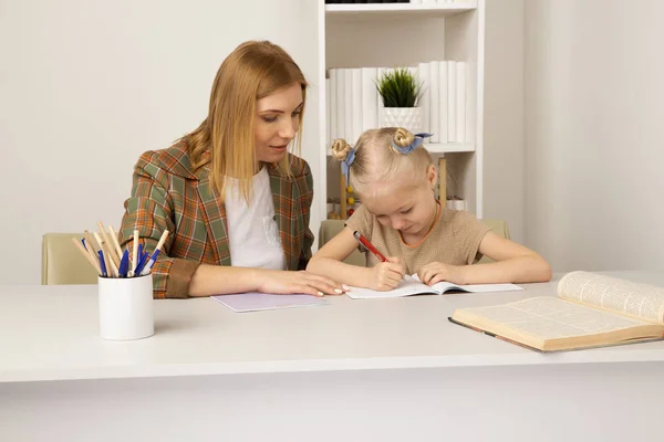 Menina com a mãe estudando juntos na mesa em casa . — Fotografia de Stock