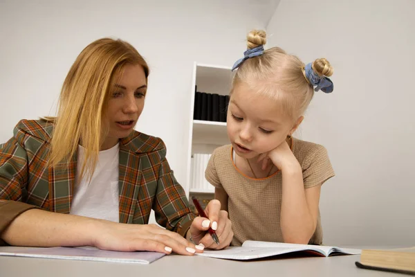 家の机で母親と一緒に勉強している小さな子供. — ストック写真