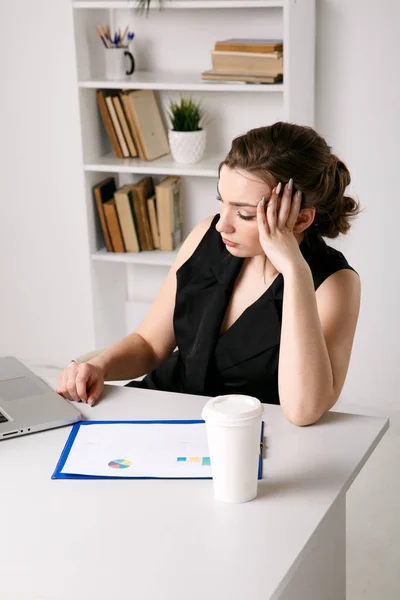 Mujer triste cansada en el estrés sentada en su lugar de trabajo y trabajando en la computadora . — Foto de Stock