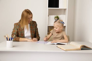 Dauhter ve anne evde oturan ve birlikte ödev yapıyor.