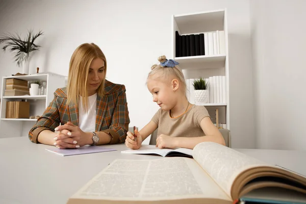 Preschool meisje studeren met moeder thuis. — Stockfoto