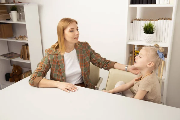 Mãe com filha conversando uns com os outros sentados na mesa . — Fotografia de Stock