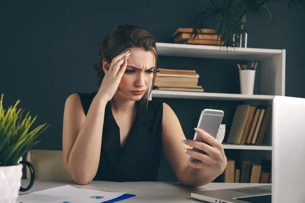 Mobile connection problem concept. Woman in office confused by bad working phone.