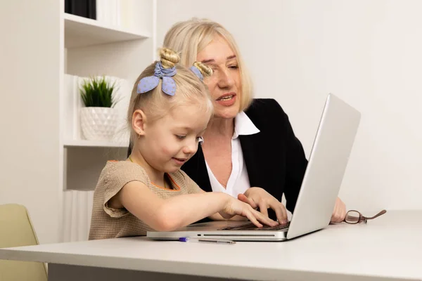 Maestra con niña aprendiendo algo en la computadora . — Foto de Stock
