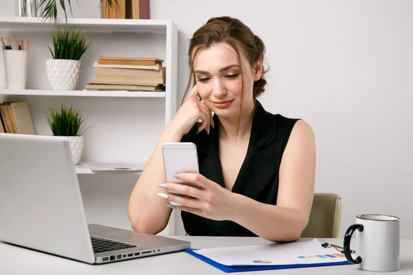 Bastante joven empresaria ver en su teléfono y sonriendo . — Foto de Stock