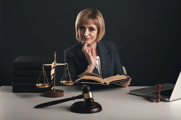 Woman lawyer with books aabout law in office sitting at the desk.