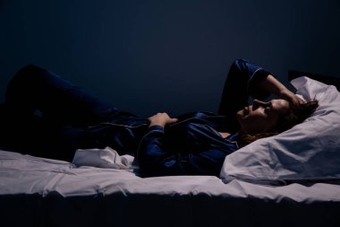 Üzgün yalnız kadın yatakta yatıyor. Uykusuzluk kavramı.