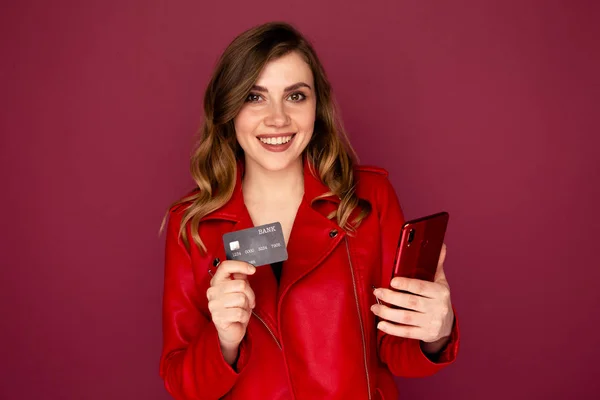 Picture of lovely lady holding credit card and mobile in a studio.