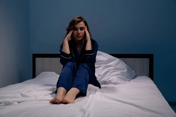 Traurige und müde Frau im Bett, die sich krank fühlt. Konzept Schlaflosigkeit und Kopfschmerzen. — Stockfoto