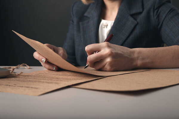 Closeup view of woman attorney writing on documents by pen.