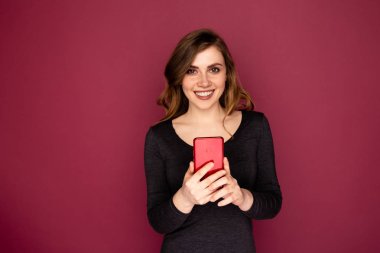 Pembe arka planda izole kırmızı mobil ile genç kadın.