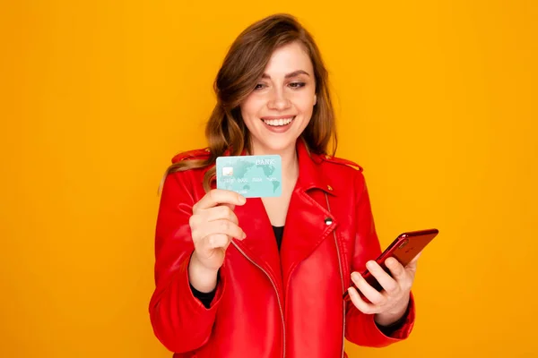 Jonge vrouw het houden van creditcard met telefoon en glimlachend. — Stockfoto