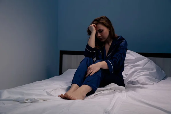 Estressado e chateado jovem mulher na cama em casa à noite . — Fotografia de Stock