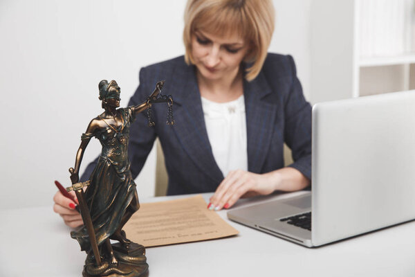 Female lawyer in the office sitting and working with paper and laptop.