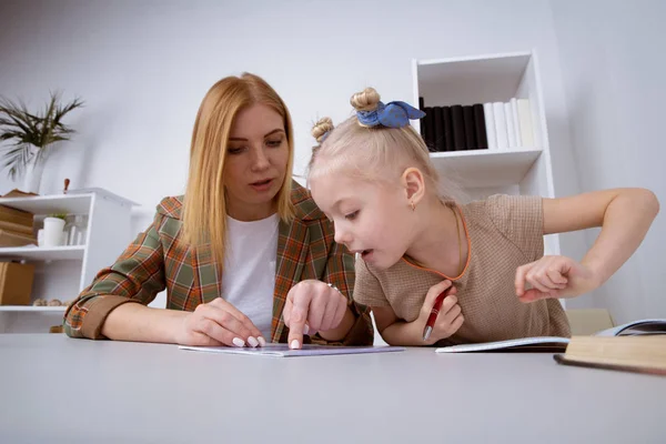 家の机で母親と一緒に勉強している小さな子供. — ストック写真