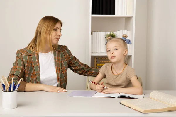 Moeder helpt kleine dochter met huiswerk. Home Education concept. — Stockfoto