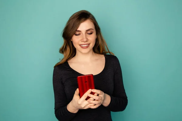 Giovane donna con cellulare rosso isolato sullo sfondo blu . — Foto Stock