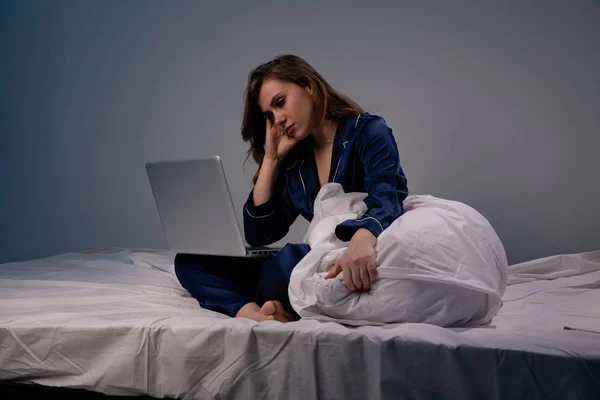Imagen de mujer cansada en casa sentada con computadora en la cama por la noche . —  Fotos de Stock
