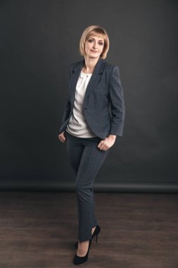 Stüdyoda takım elbiseli kadın gri arka planda izole.