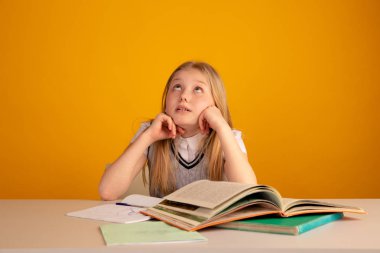 Üzgün ve yorgun bebek masada oturan ve ev ödevi yapıyor.
