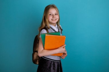 Bir okul elbisesi içinde küçük kız mavi arka plan izole ayakta.