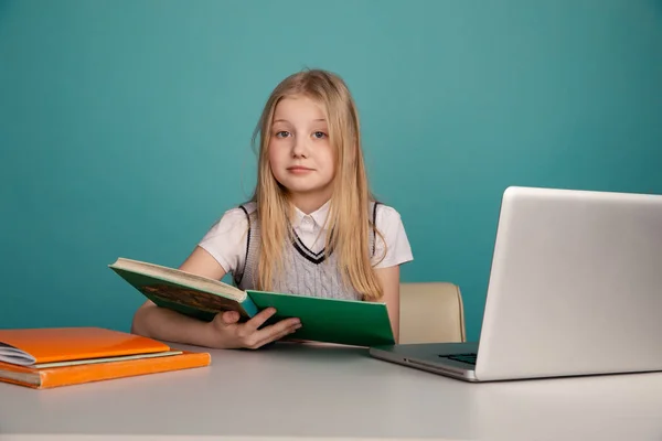 Küçük kız bilgisayar önünde kitap ile sınıfta oturan. — Stok fotoğraf