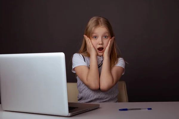 Verbaasde jonge student die voor de computer in de klas zit. — Stockfoto