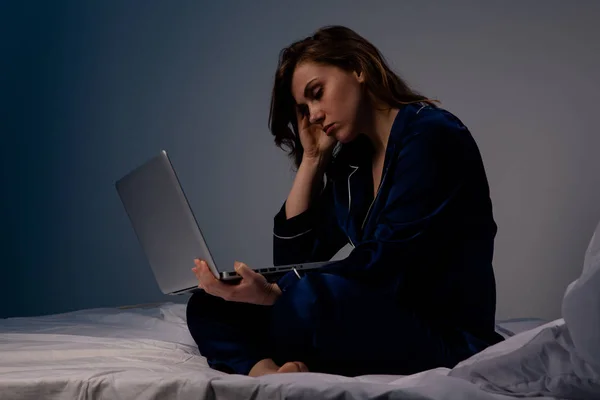 Mujer frustrada en casa sentada en la cama con computadora . —  Fotos de Stock