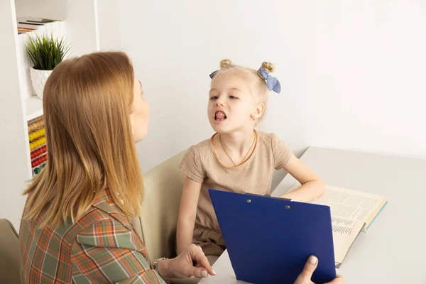 Schattig meisje met spraak therapeut in kabinet trainiing uitspraak. — Stockfoto