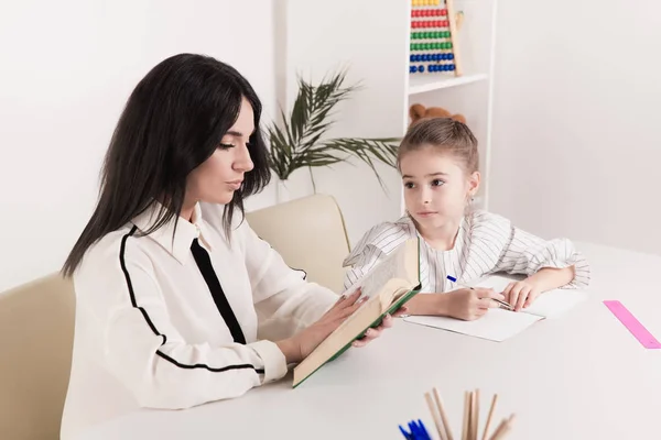 Pretty family concept. Mom and daughter sitting together and studying at home. — Stock Photo, Image