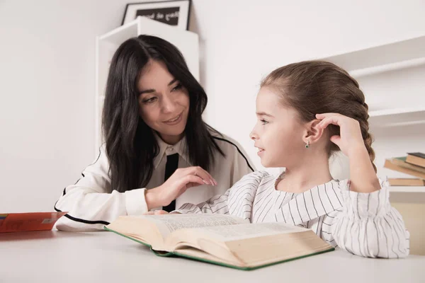 Mom doing homework with daughter and reading book. — Stock Photo, Image