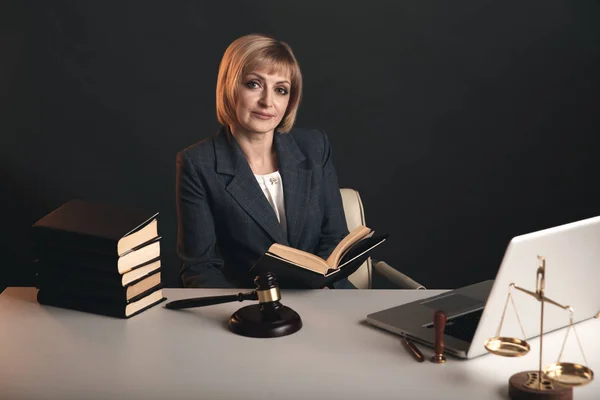 Female jurist isolated at the dark background. Books and gavel with justice scales. — Stock Photo, Image