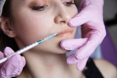 Doktor güzellik uzmanı sıkma ve güzel, genç bir kadının bir güzellik, yüz cilt kırışıklıkları yumuşatma için gençleştirici yüz enjeksiyonları yordam bulunur