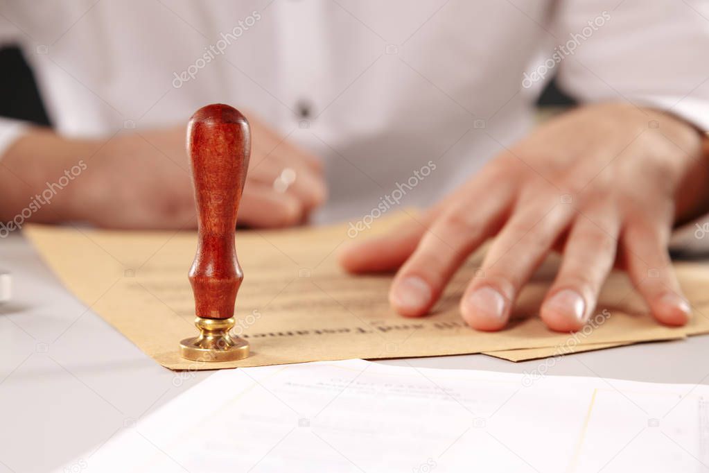 Close up on man notary public hand ink stamping the document. Notary public