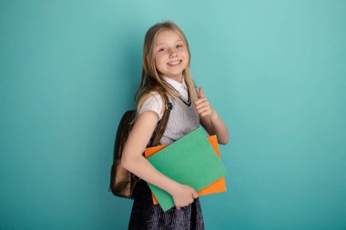 Sırt çantası izole bir okul elbisesi içinde sevimli gülümseyen kız.