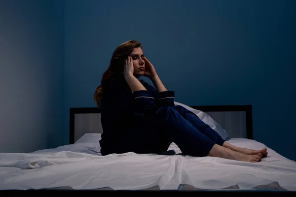 Bild der Frau, die an Schlaflosigkeit leidet und zu Hause schläft, wenn sie auf dem Bett sitzt. — Stockfoto