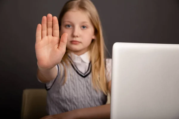 Ernstig klein meisje toont stop teken geïsoleerd in de donkere kamer. — Stockfoto