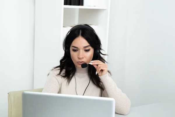 Mujer feliz asistente del centro de llamadas sentado en el escritorio y la computadora de trabajo haciendo diferentes llamadas . — Foto de Stock