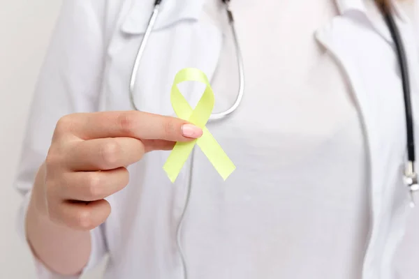 Yellow ribbon in doctors hand isolated.