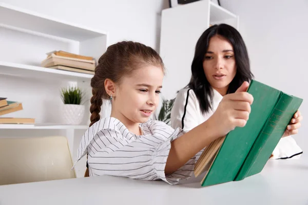 Mother and daughter reading time. Learning together sitting at the table. — Stock Photo, Image