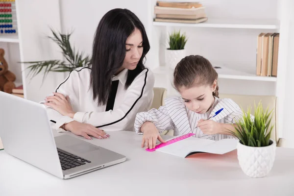 Moeder en dochter zitten met computer samen aan de balie. — Stockfoto