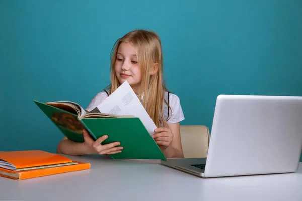 Petite fille assise dans la salle de classe avec livre devant l'ordinateur . — Photo