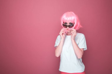 Retro moda konsepti. Siyah gözlüklü pembe saçlı ve parlak pembe stüdyoda beyaz T-shurt ile kadın.